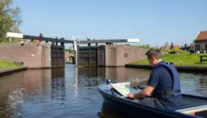 Een cursist met een reddingsvest bestuurt een motorsloep en bekijkt een kaart op de console.