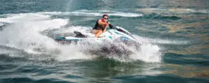 Man met reddingsvest vaart op hoge snelheid met een jetski over het water