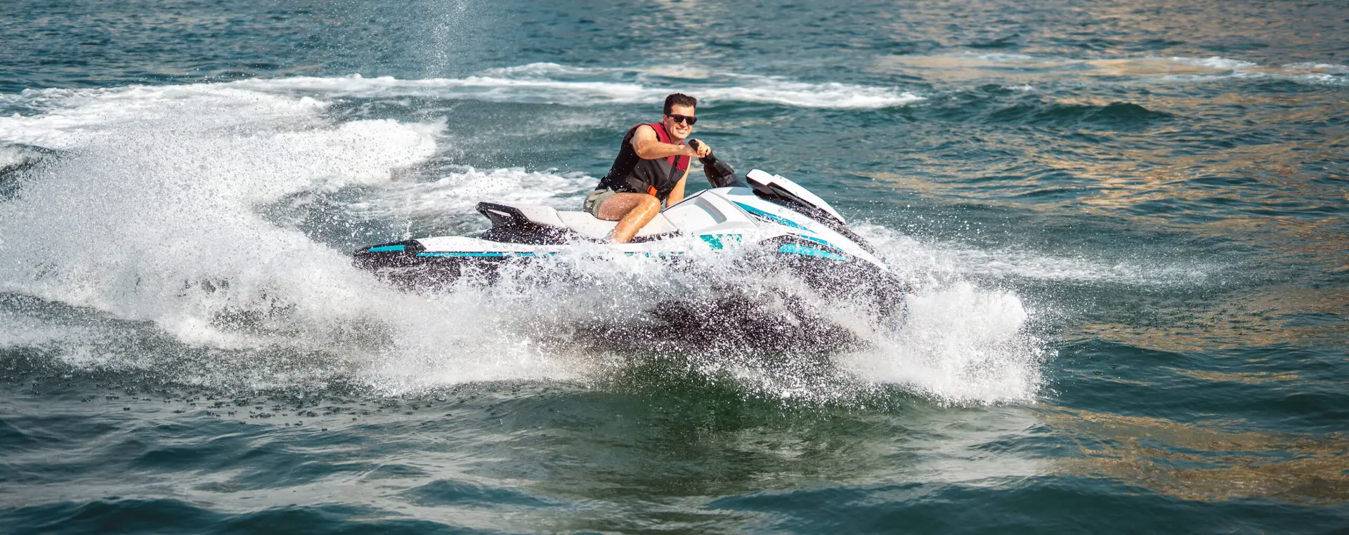 Man met reddingsvest vaart op hoge snelheid met een jetski over het water
