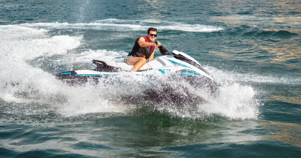 Man met reddingsvest vaart op hoge snelheid met een jetski over het water